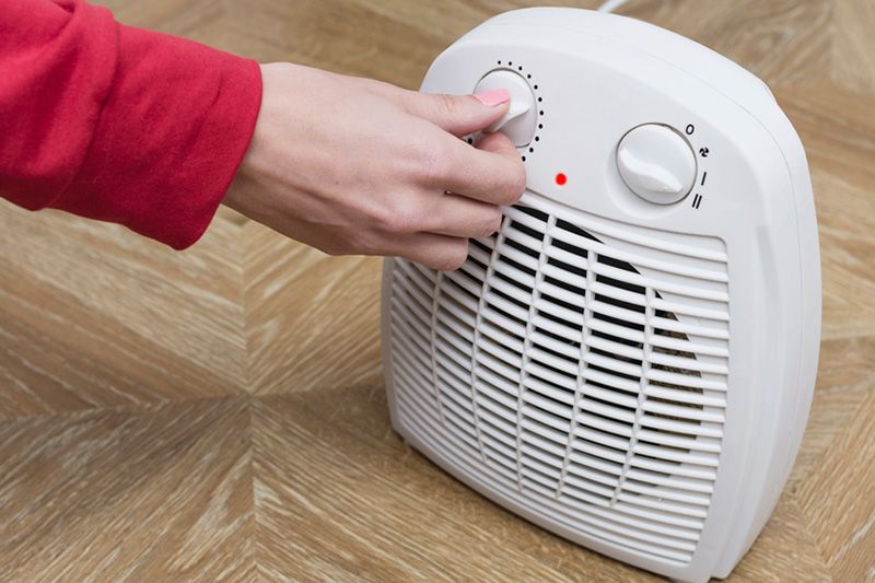 A person uses a heater. How Can I Lower My Heating Bill This Winter?