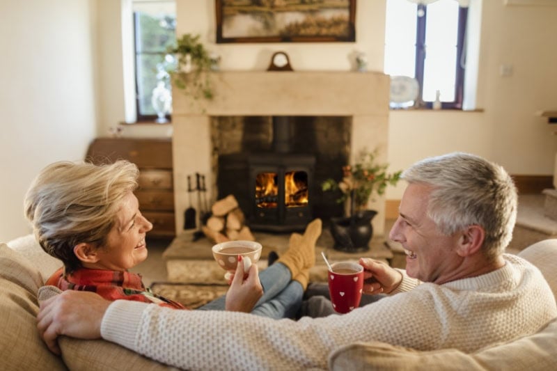How to Keep Warm During Extreme Cold Weather. Photo of a couple enjoying a hot beverage by a fire