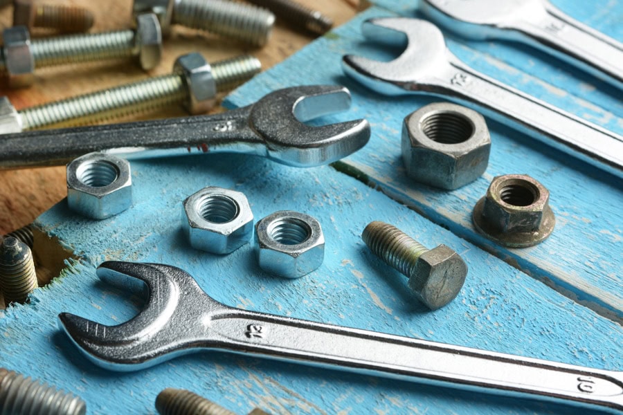 Bolts and english wrenches on wooden table. Heat pump maintenance tips.