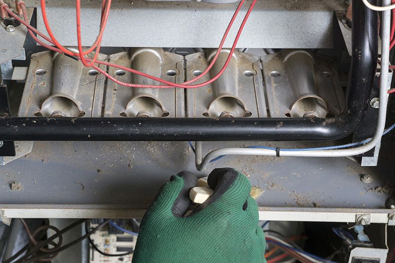 Image of someone working on a furnace. Why Isn't My Furnace Heating My Entire Home?